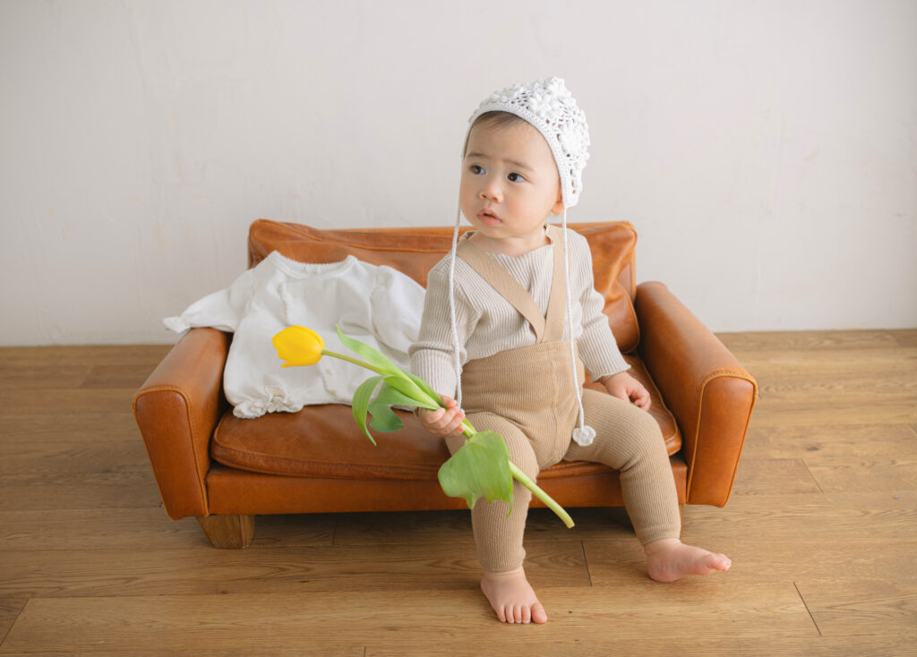 ベビーフォト　花と持ってソファに座る男の子